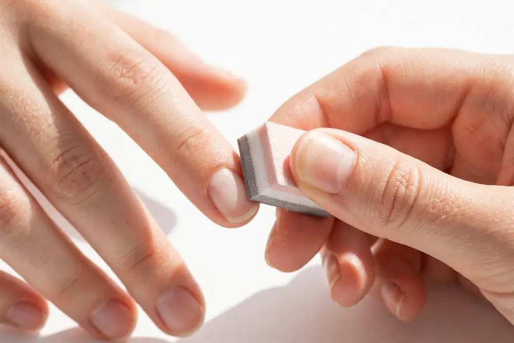 Gently buffing natural fingertips before application